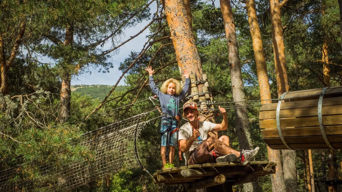 Father and child embrace adventure on a forest zipline in Cercedilla, Spain.